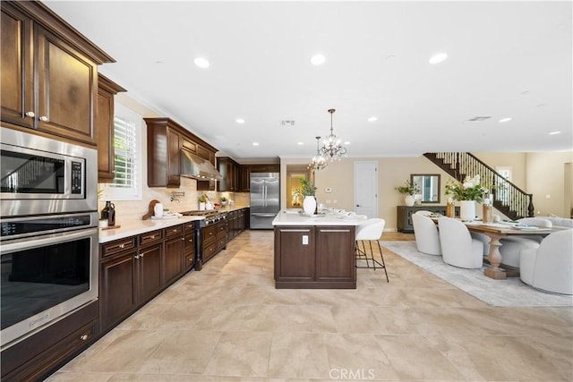 kitchen with open floor plan, built in appliances, extractor fan, crown molding, and a kitchen bar