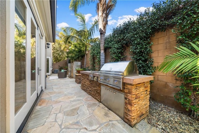 view of patio / terrace featuring an outdoor kitchen, grilling area, and fence