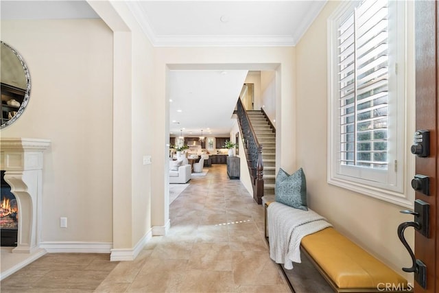 entrance foyer featuring ornamental molding, a high end fireplace, stairway, and baseboards