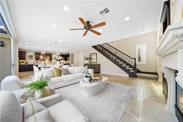 living area featuring recessed lighting, a fireplace with flush hearth, visible vents, stairs, and plenty of natural light