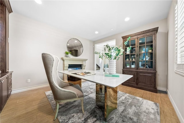 office area featuring a glass covered fireplace, light wood-style flooring, baseboards, and recessed lighting