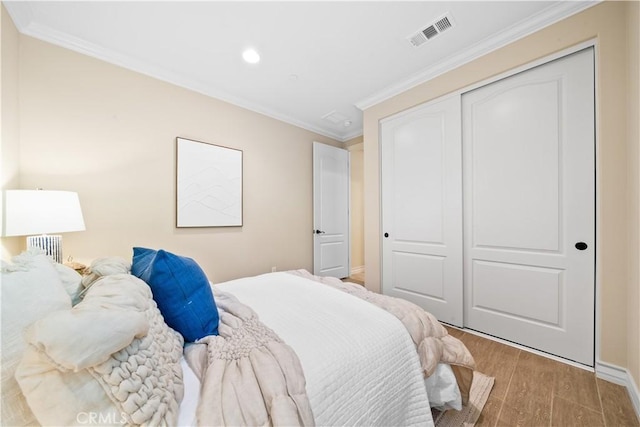 bedroom with recessed lighting, wood finished floors, visible vents, ornamental molding, and a closet