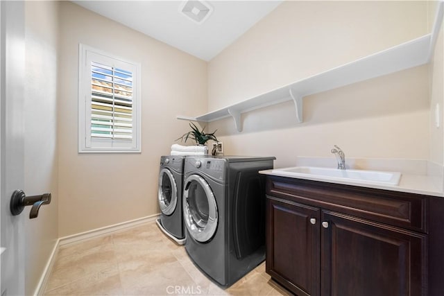 clothes washing area with light tile patterned floors, cabinet space, a sink, washer and dryer, and baseboards