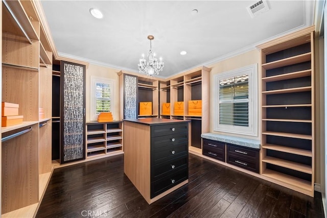 spacious closet featuring dark wood-style floors, visible vents, and a notable chandelier