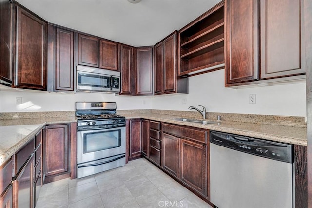 kitchen with dark brown cabinetry, light stone countertops, stainless steel appliances, open shelves, and a sink