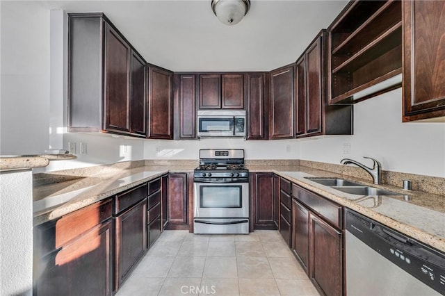 kitchen featuring light tile patterned floors, appliances with stainless steel finishes, a sink, and light stone countertops