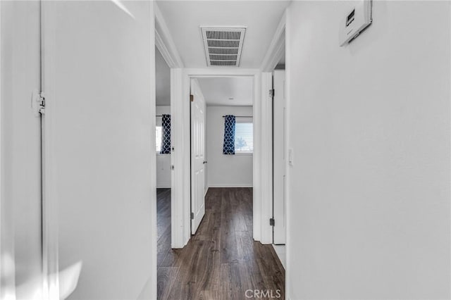 corridor with dark wood-type flooring, visible vents, and baseboards