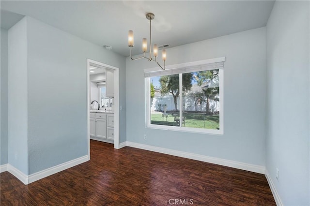 unfurnished dining area featuring baseboards, visible vents, dark wood-style floors, a chandelier, and a sink