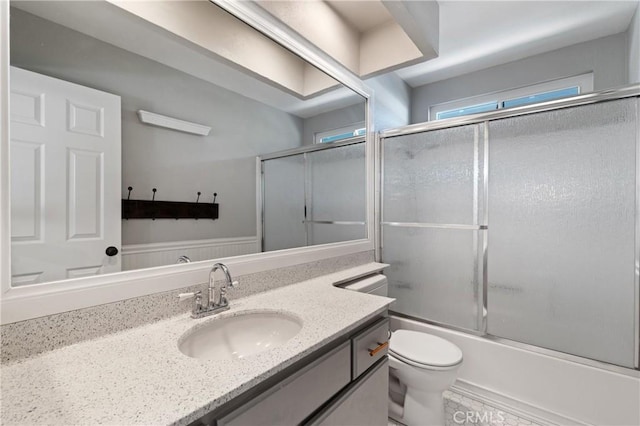 bathroom with shower / bath combination with glass door, vanity, and toilet