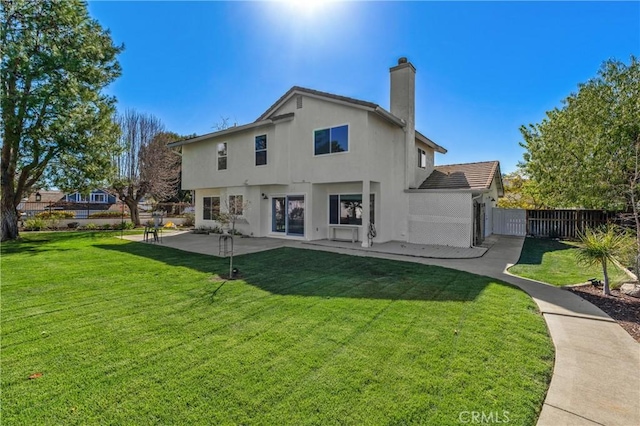 rear view of house with a lawn, a chimney, fence, a patio area, and stucco siding