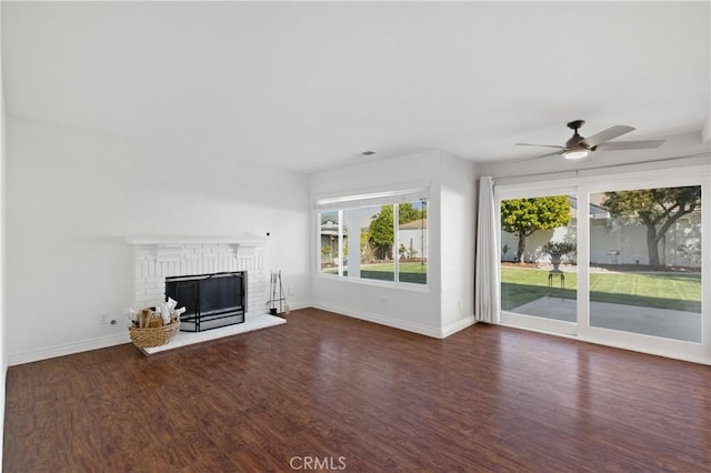 unfurnished living room with ceiling fan, a fireplace, baseboards, and wood finished floors