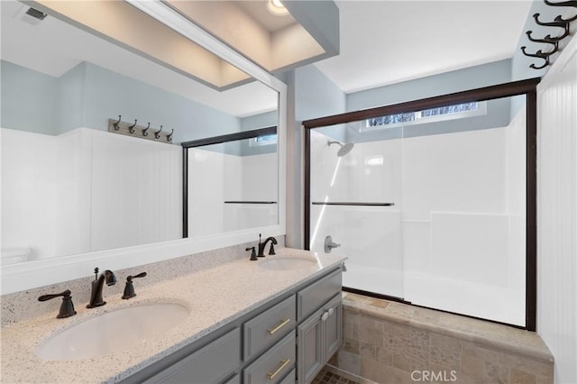 bathroom with a shower with shower door, a sink, visible vents, and double vanity