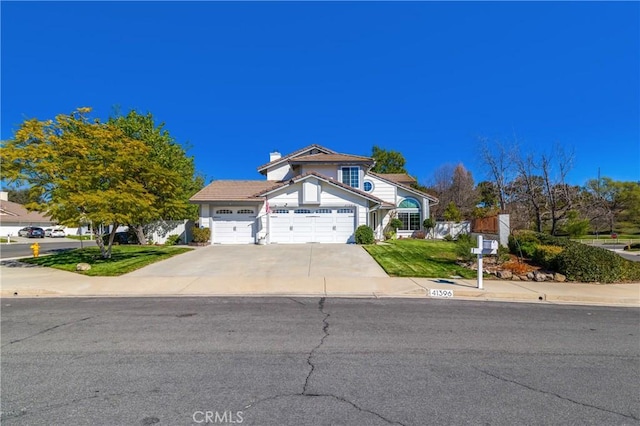 view of front of house featuring a chimney, concrete driveway, an attached garage, fence, and a front lawn