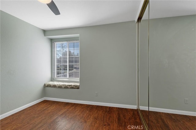 spare room with ceiling fan, wood finished floors, and baseboards