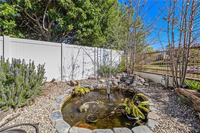 view of yard featuring a fenced backyard and a garden pond