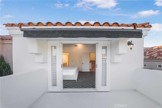 view of exterior entry with stucco siding and a tiled roof