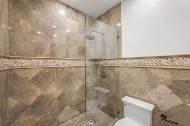 bathroom featuring a tile shower, tile walls, and toilet