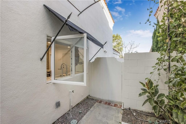 view of side of property featuring fence and stucco siding