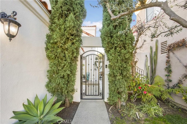 view of exterior entry featuring a gate and stucco siding