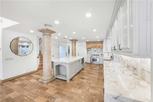 kitchen with decorative columns, tasteful backsplash, recessed lighting, high end stainless steel range oven, and a kitchen island