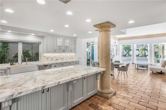 kitchen with glass insert cabinets, a sink, decorative columns, and recessed lighting