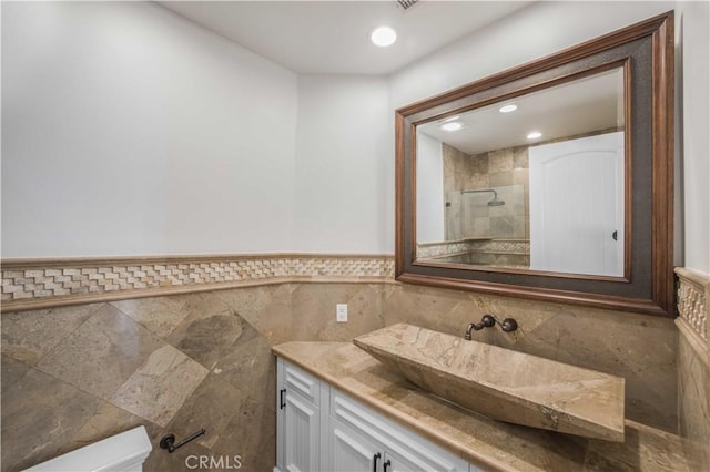 bathroom featuring a wainscoted wall, tiled shower, vanity, and recessed lighting