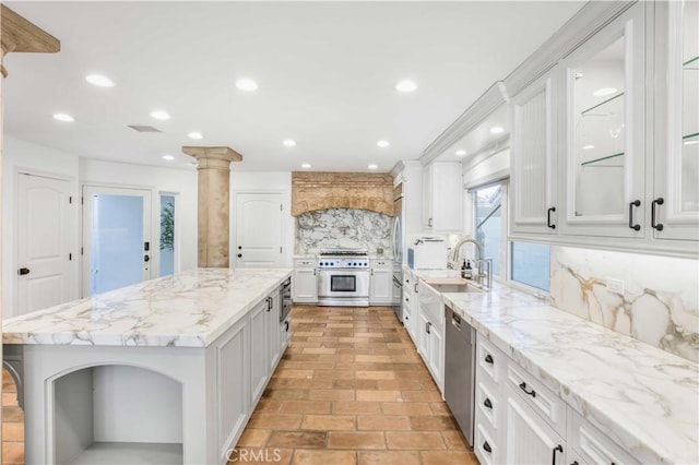 kitchen with backsplash, appliances with stainless steel finishes, white cabinets, a kitchen island, and light stone countertops