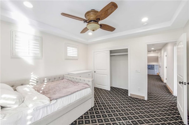 bedroom featuring baseboards, a tray ceiling, a closet, and recessed lighting