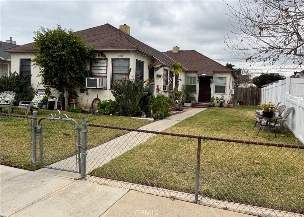 bungalow-style home with a shingled roof, a fenced front yard, a gate, a front yard, and stucco siding