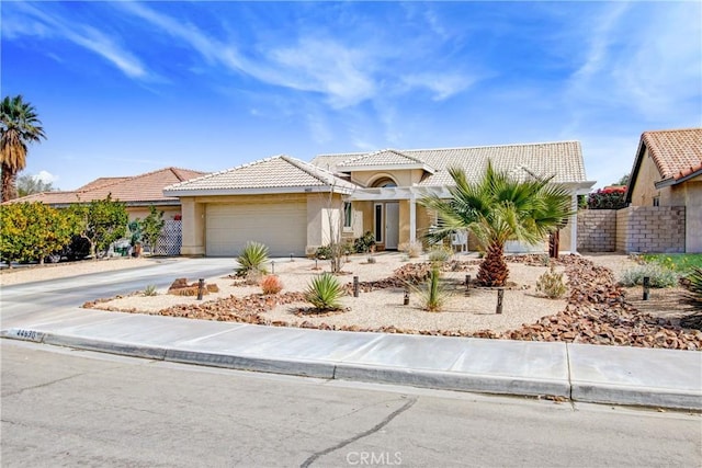 view of front of house with an attached garage, fence, concrete driveway, a tiled roof, and stucco siding