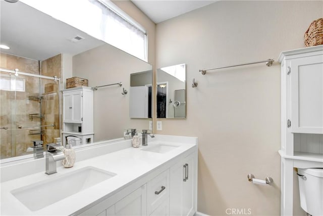 full bathroom featuring double vanity, a stall shower, a sink, and toilet