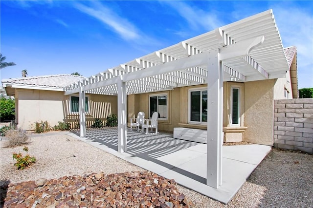 rear view of house with a patio area, fence, and stucco siding