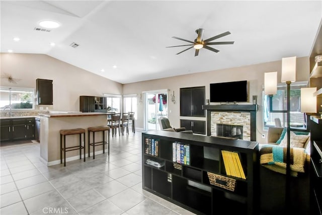 living room featuring a wealth of natural light, lofted ceiling, ceiling fan, and light tile patterned floors