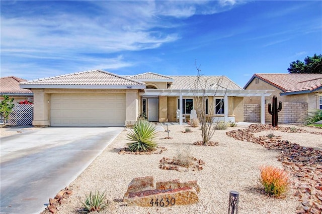 ranch-style home with driveway, an attached garage, a tiled roof, and stucco siding