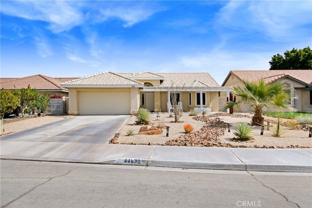 view of front of property with an attached garage, a tile roof, concrete driveway, and stucco siding