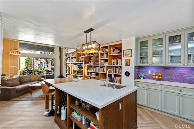 kitchen with a center island with sink, open shelves, decorative backsplash, open floor plan, and a sink