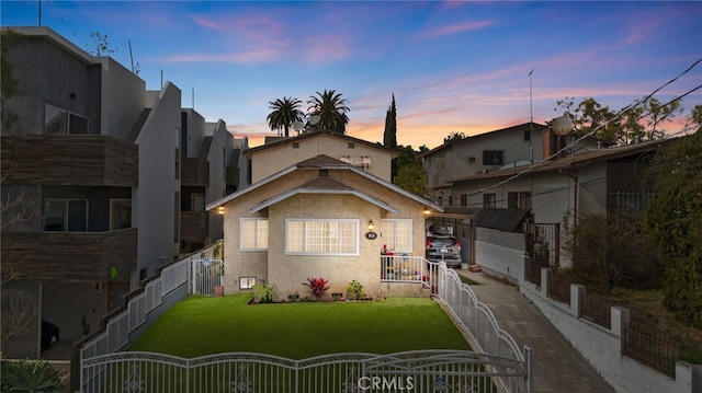 view of front of property featuring driveway, a front yard, fence, and stucco siding