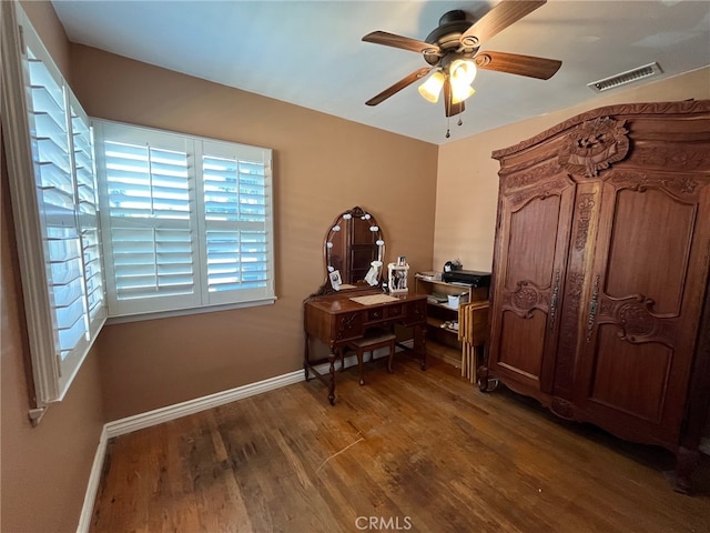 office space with a ceiling fan, visible vents, baseboards, and wood finished floors