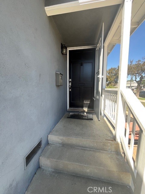 property entrance featuring a balcony, visible vents, and stucco siding