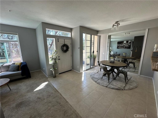 foyer featuring a textured ceiling, light tile patterned floors, and baseboards