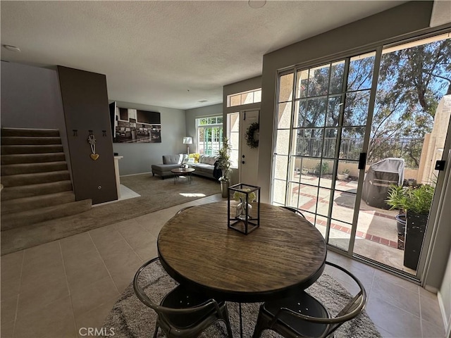 dining space with stairway, a textured ceiling, and tile patterned floors