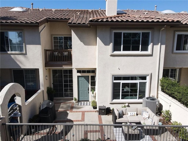 back of house with central AC, outdoor lounge area, a chimney, and stucco siding