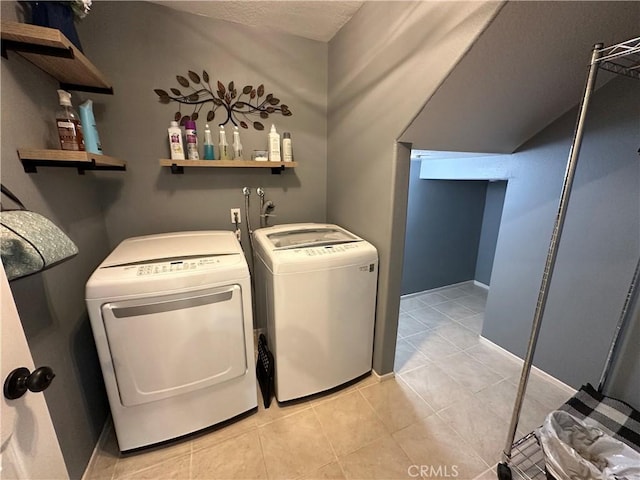 laundry room featuring light tile patterned floors, laundry area, washing machine and dryer, and baseboards