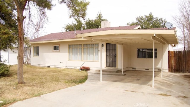 back of house featuring a chimney, an attached carport, crawl space, fence, and a yard