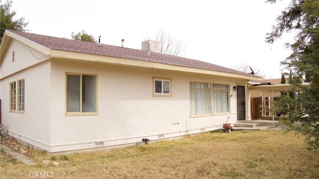 back of property featuring crawl space, roof with shingles, and a yard