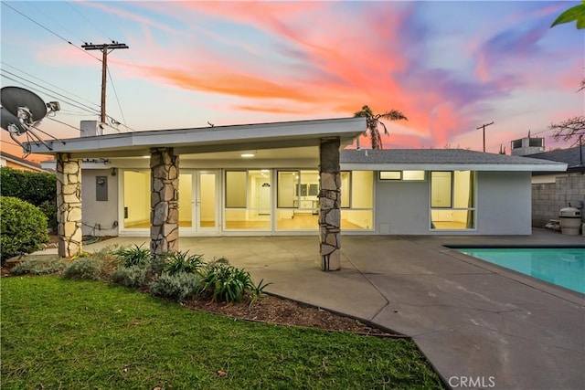 back of house featuring an outdoor pool, a patio area, and stucco siding