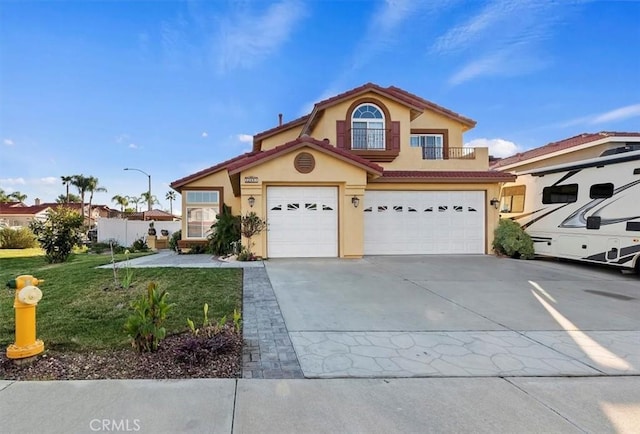 view of front of house with an attached garage, a balcony, driveway, stucco siding, and a front yard