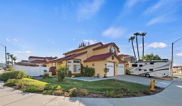 mediterranean / spanish-style house with a garage, fence, concrete driveway, stucco siding, and a front lawn