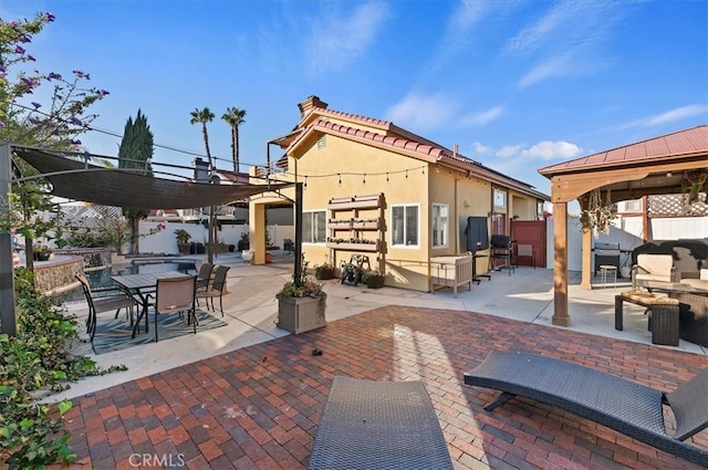 view of patio featuring fence, outdoor dining area, area for grilling, and a gazebo