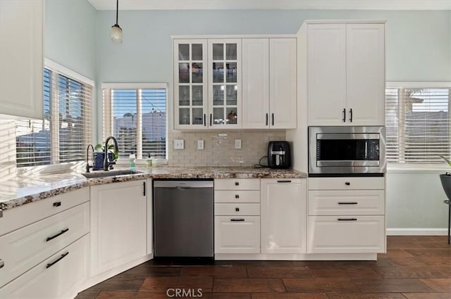 kitchen featuring stainless steel appliances, backsplash, a sink, and glass insert cabinets